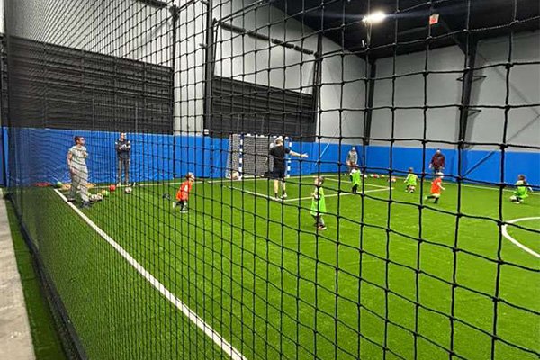 Kids training on the indoor field with coaches at CJ Lasso Arena
